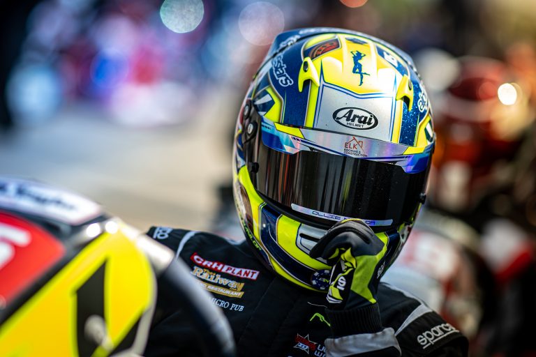 Close up of Ollie Naylor Racings helmet with tinted visor blue and yellow arai helmet